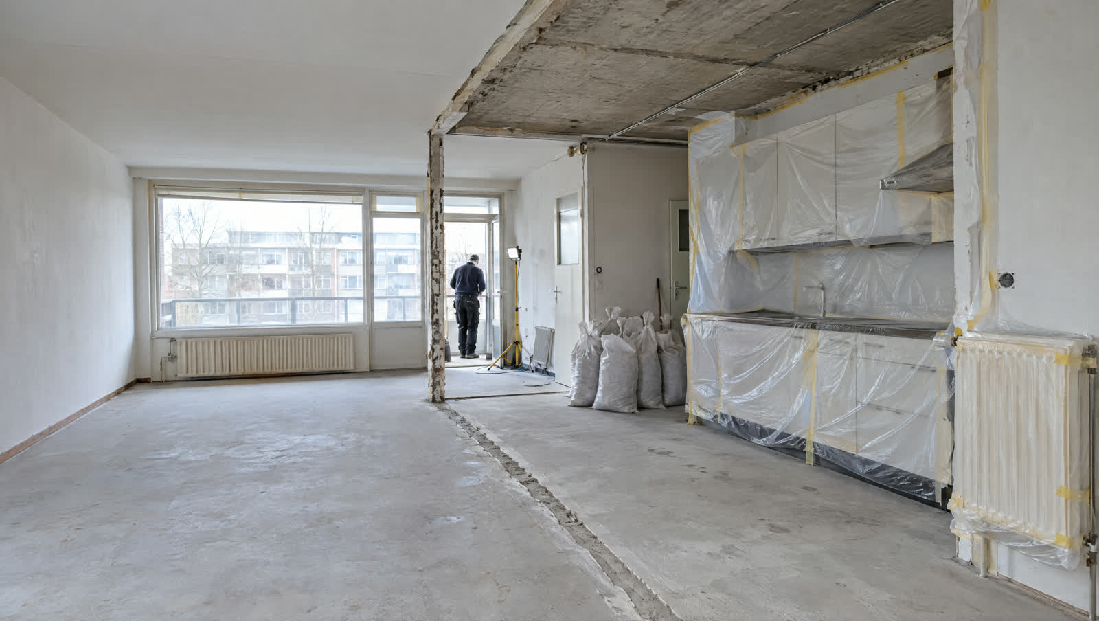Appartement tijdens binnensloop, met de te behouden keukenwand in folie afgeschermd