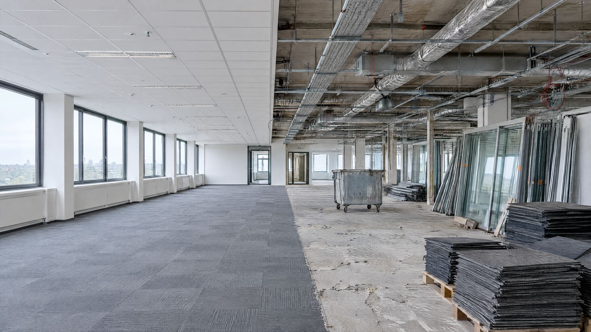 Kantoorvloer die casco wordt gemaakt, met tapijttegels op pallets en een open plafond
