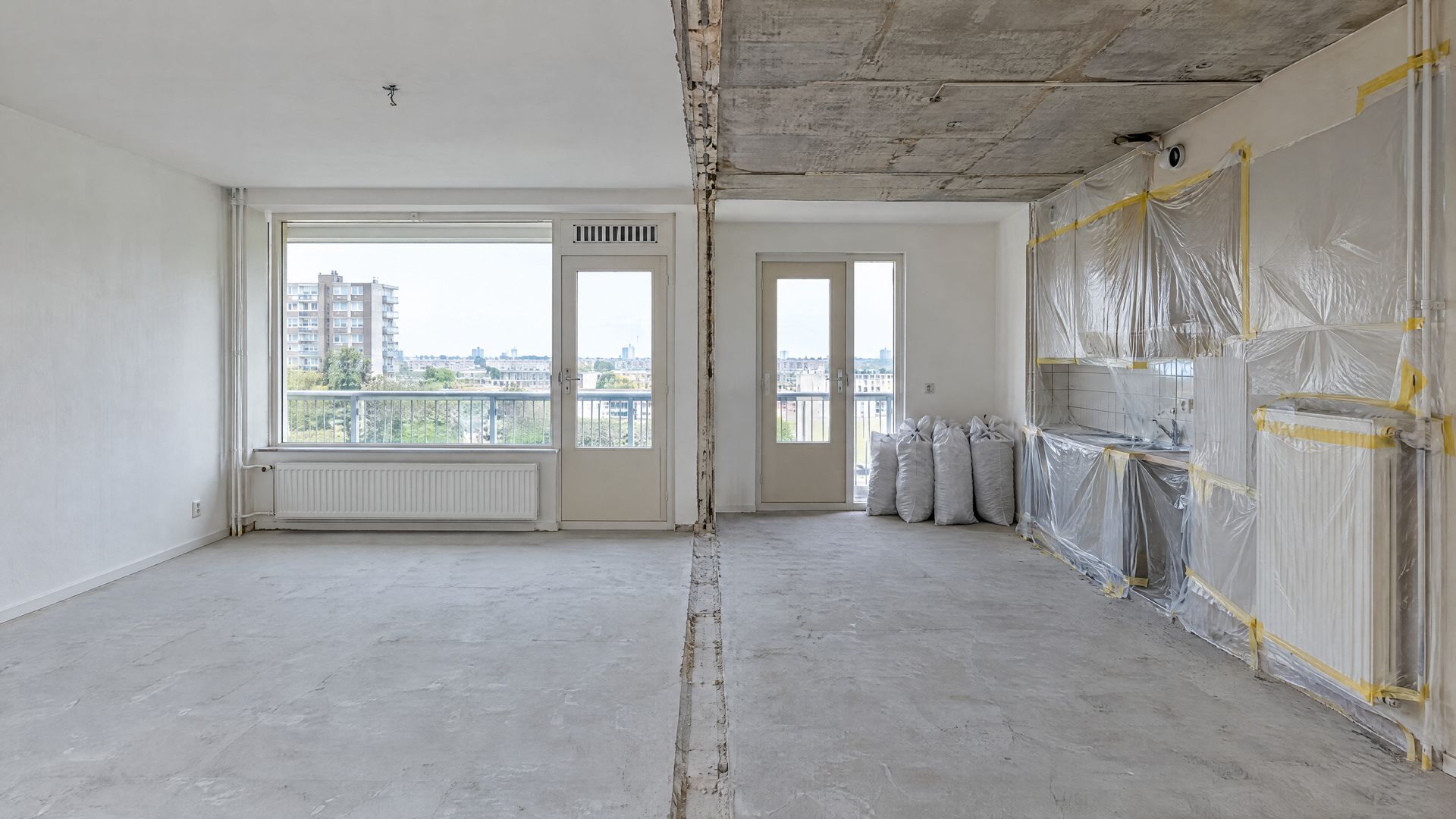 Appartement tijdens binnensloop, met een in folie afgeschermde keukenwand