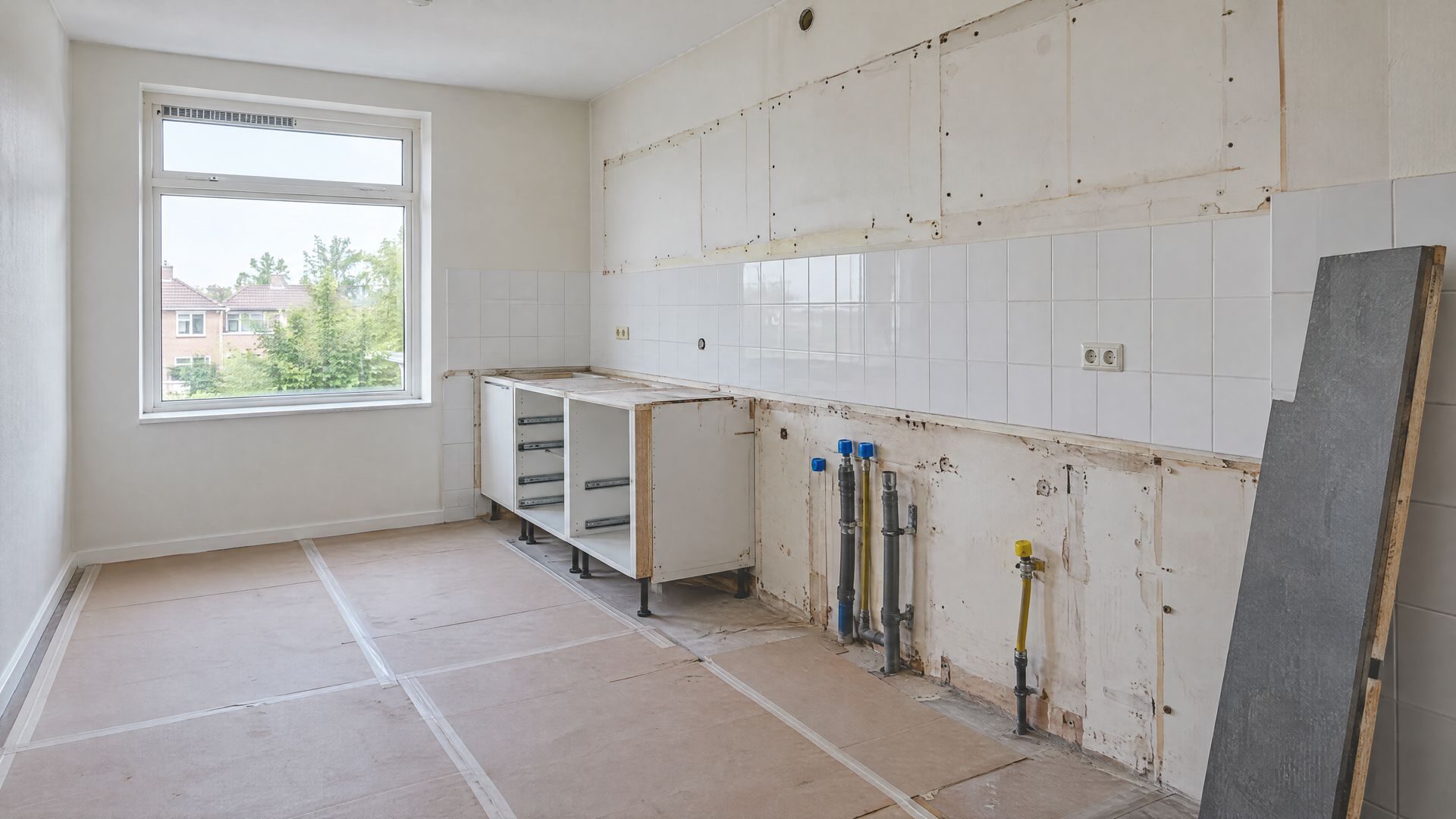 Keuken in demontage met afgedopte leidingen en het werkblad tegen de wand