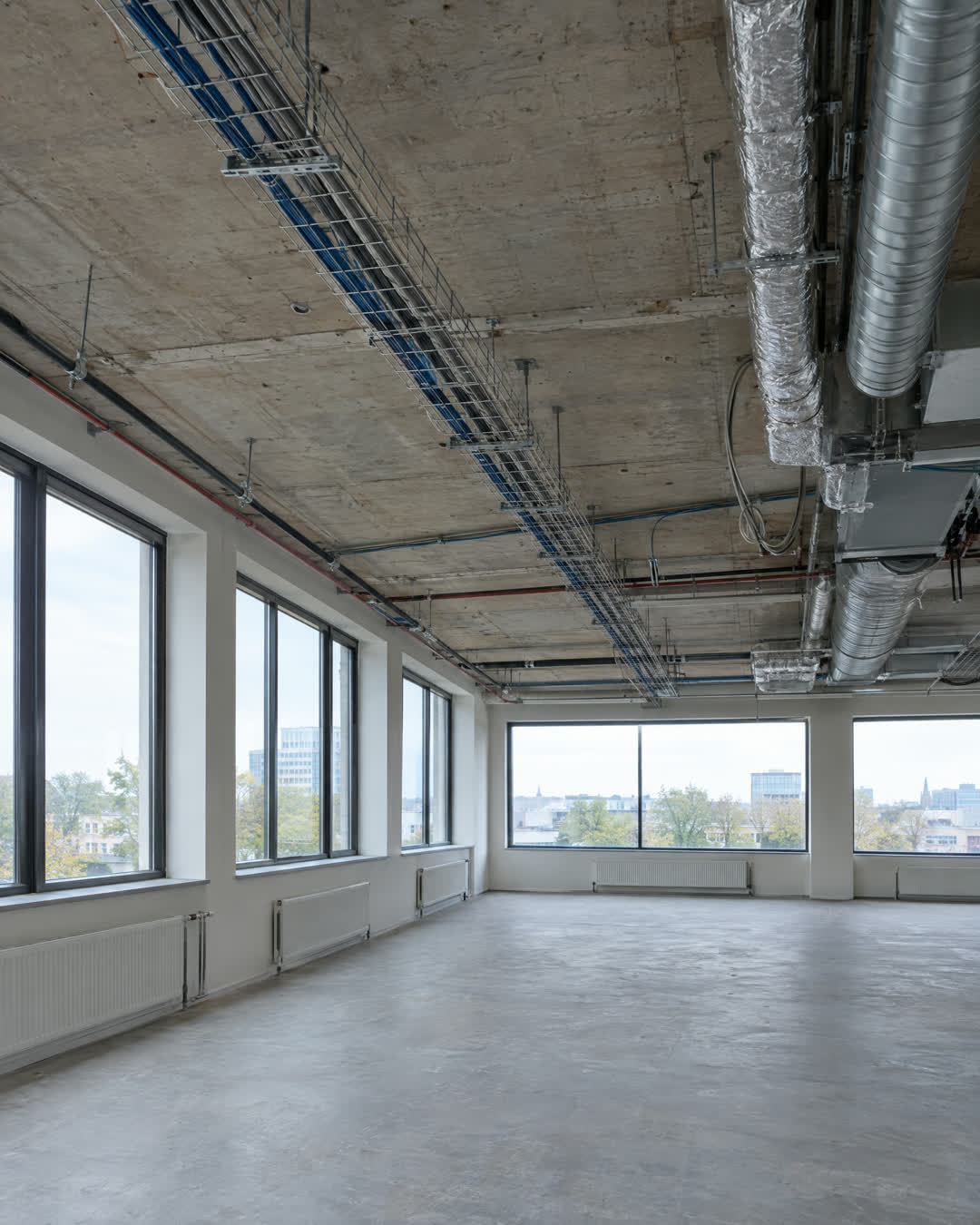 Na: dezelfde ruimte met het systeemplafond verwijderd tot op de betonvloer