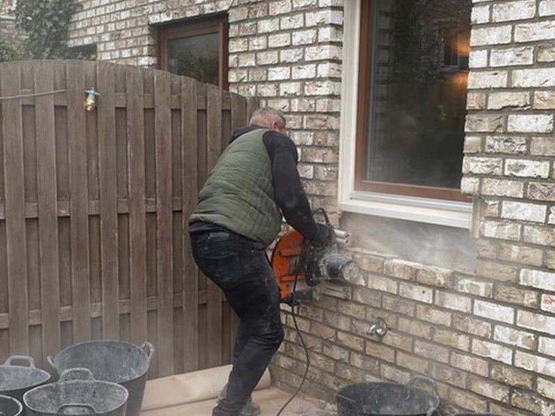Vakman zaagt een opening in een bakstenen muur