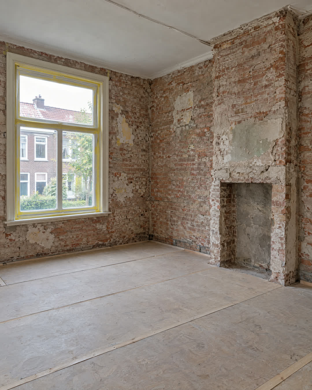 Na: dezelfde kamer kaal tot op het metselwerk, klaar voor de verbouwing