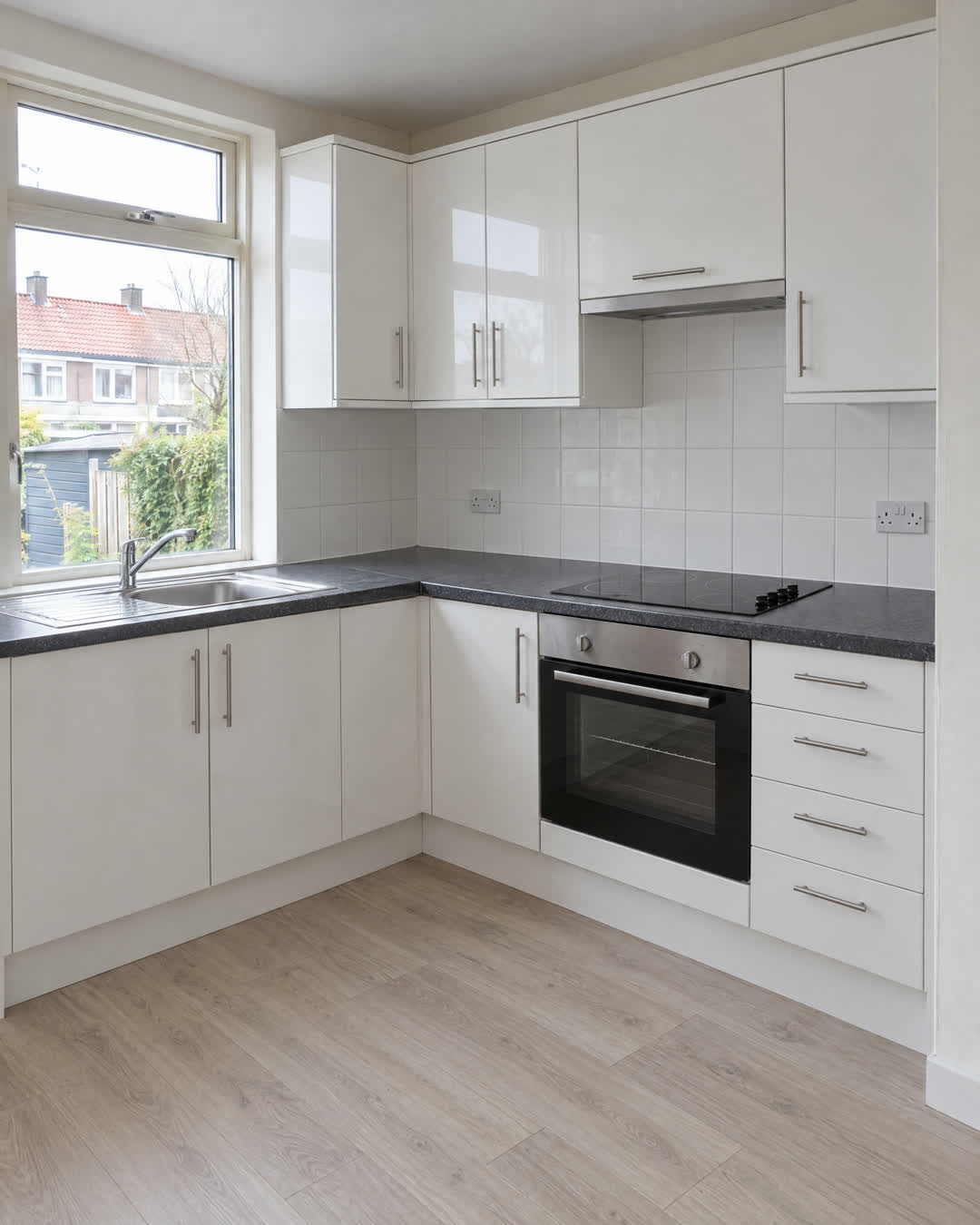 Voor: keuken met witte kasten, werkblad en tegelwand